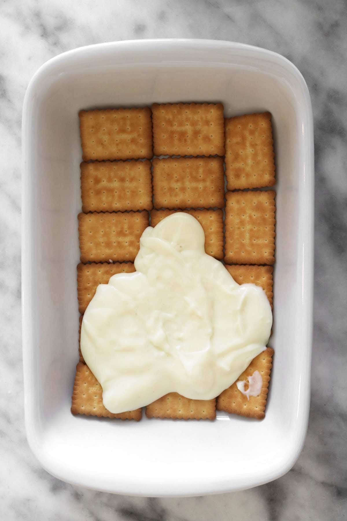 adding the custard layer onto the biscuits
