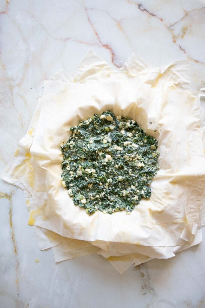 adding the spinach and feta filling on top of the filo sheets