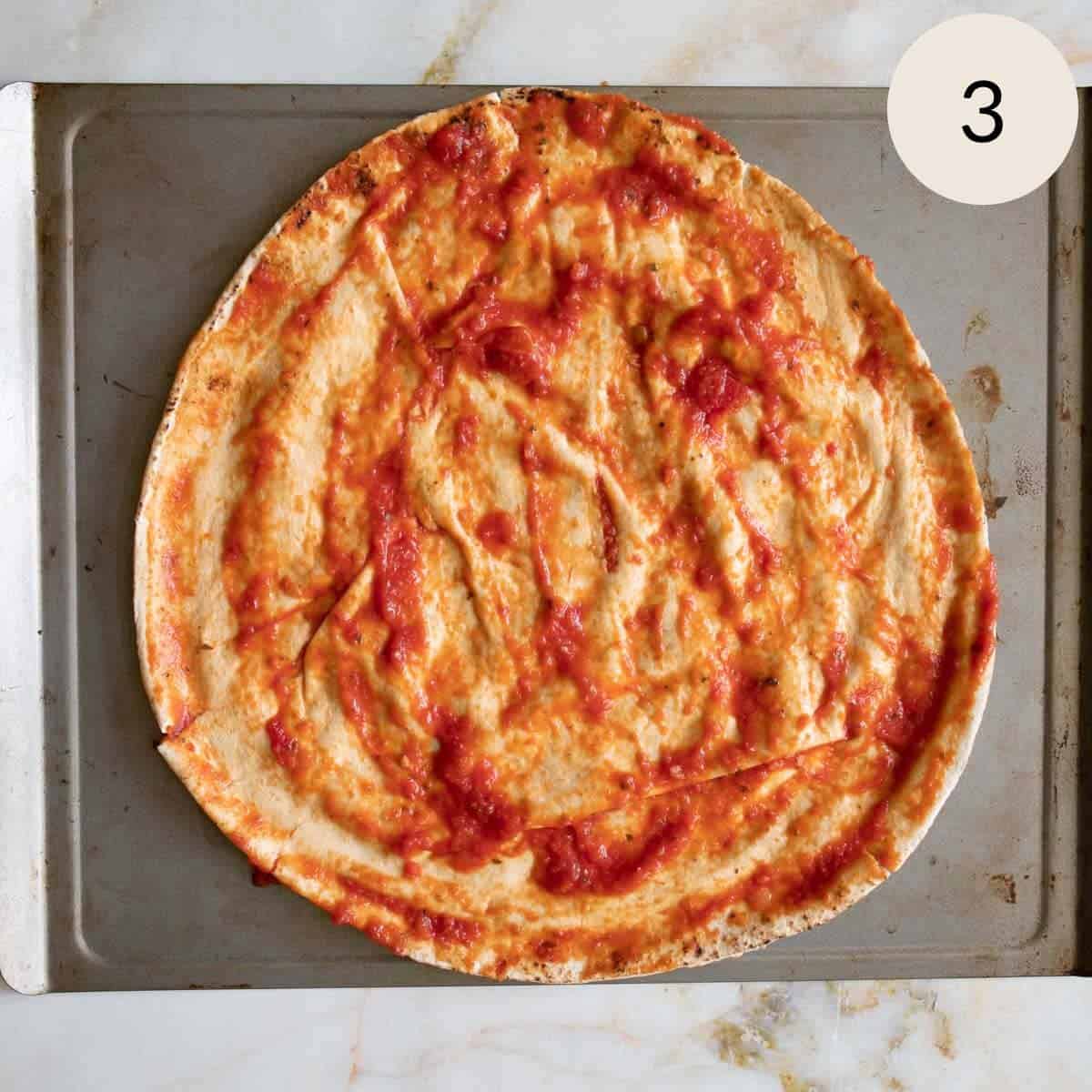 spreading tomato sauce all over the Lebanese pita bread