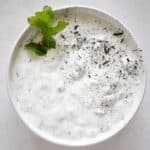 cucumber mint yogurt in a bowl with fresh mint and dried mint