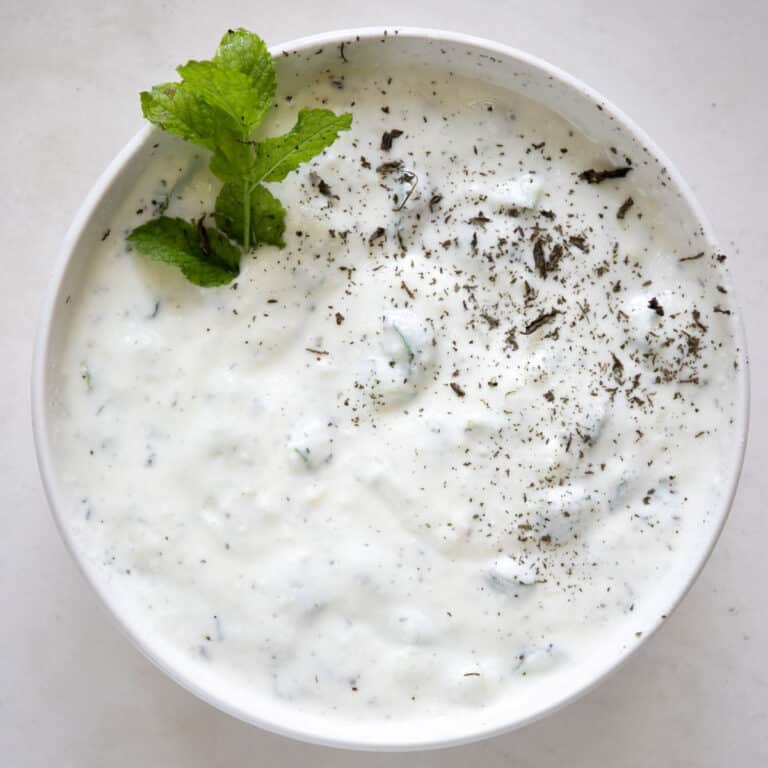 cucumber mint yogurt in a bowl with fresh mint and dried mint
