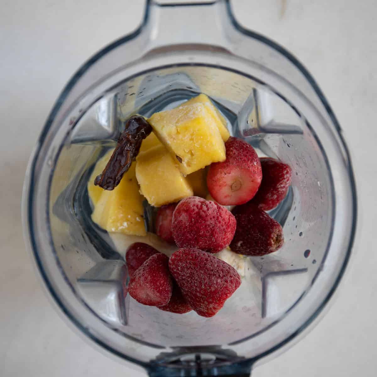 add the frozen strawberries, frozen banana, pineapple, and Medjool date to blender with water