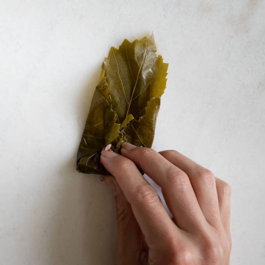 roll the grape leaf by tucking the sides