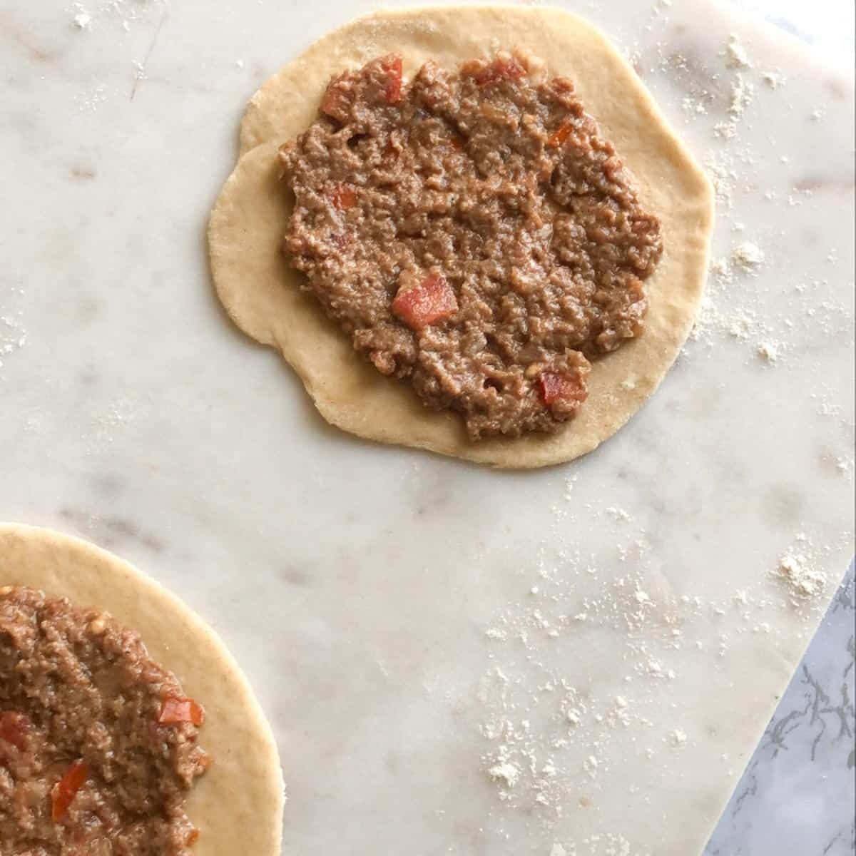 adding the minced meat on top of the dough