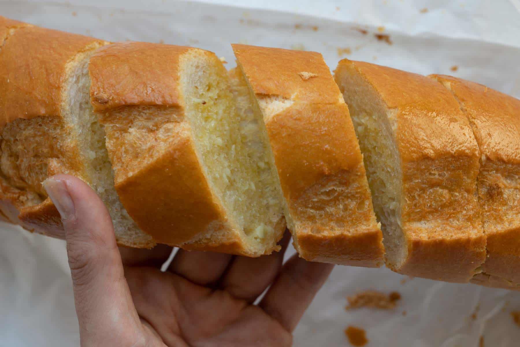 opening the french baguette to reveal the garlic butter.