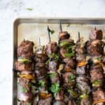 grilled beef shish kabob skewers on a baking sheet.