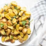 quartered baby Yukon gold potatoes on a plate with herbs.