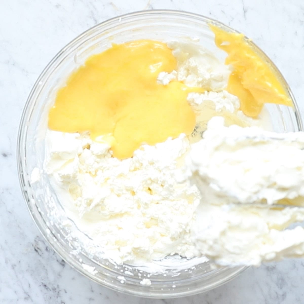whipped cream, mascarpone, sugar, and pasteurized egg yolks mixed in a bowl.