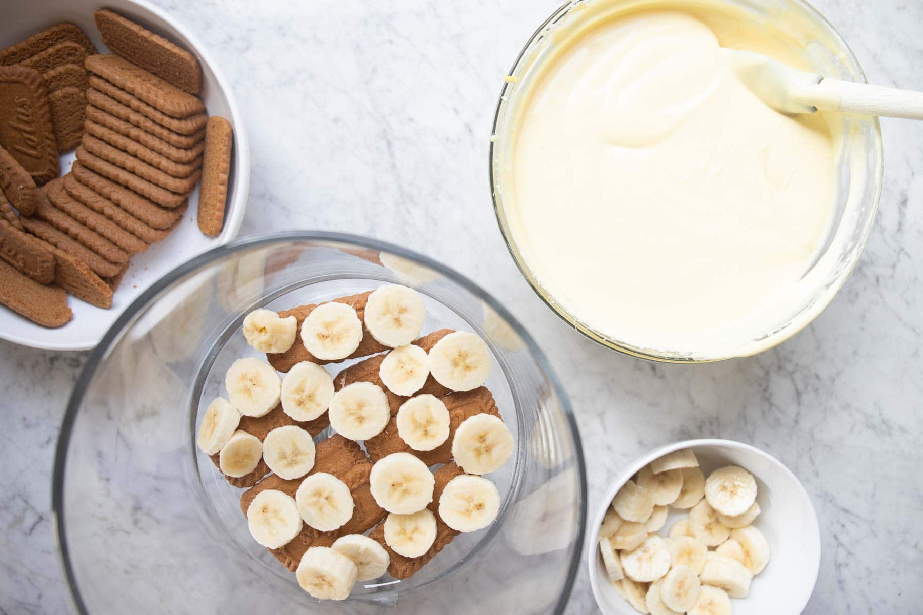 assembling the banana pudding in a trifle dessert bowl.