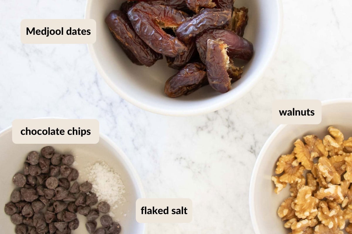 Ingredients needed to make cookie dough date balls. Ingredients include walnuts, chocolate chips, medjool dates, and flaked salt.