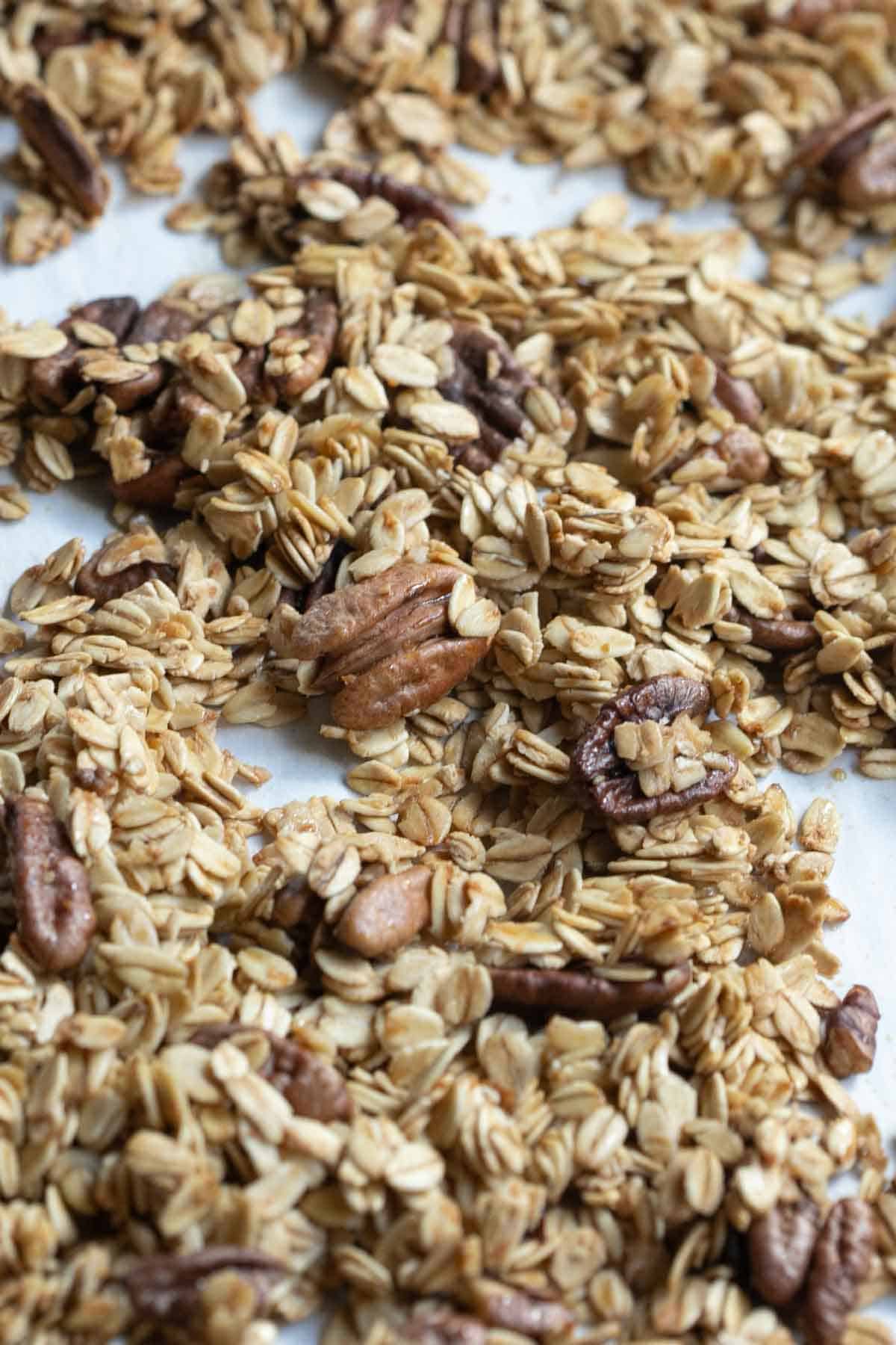 close up view of homemade granola with maple syrup and shelled pecans.