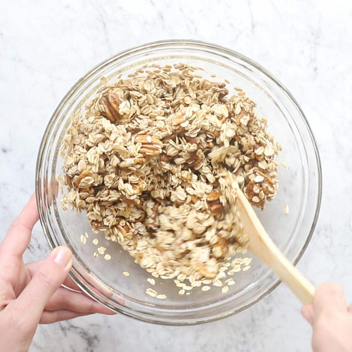 adding oats, shelled pecans, maple syrup, salt, and olive oil to a bowl and mixing.