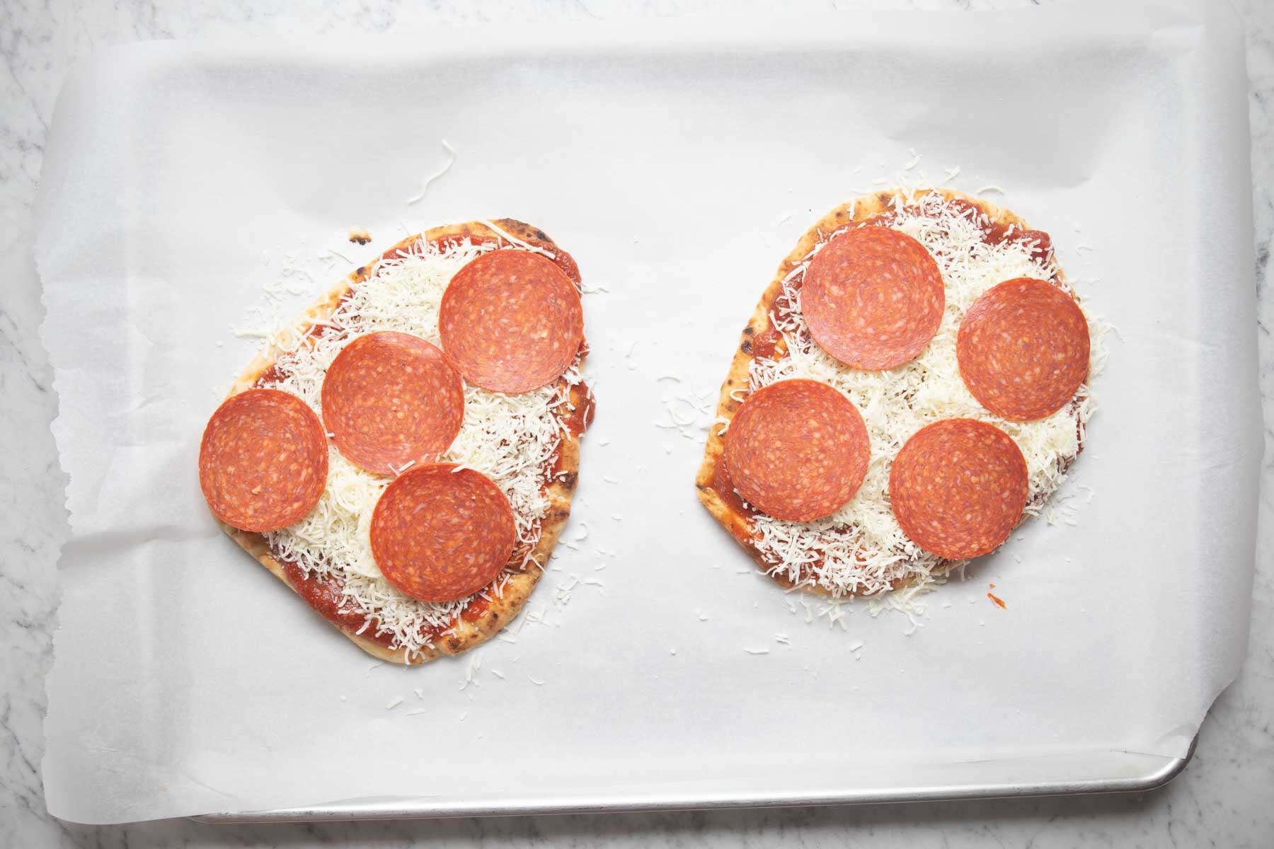 naan pizzas before going into the oven.