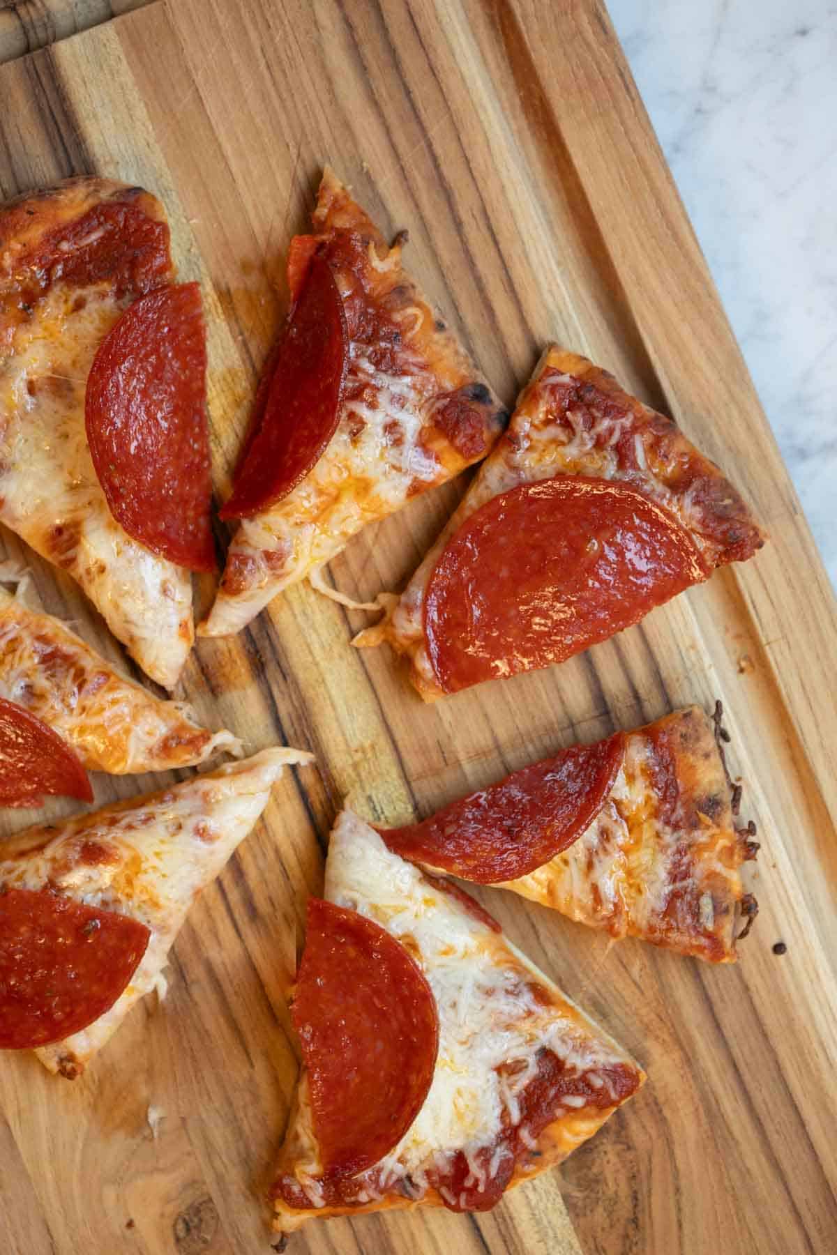naan pizza slices on a cutting board.