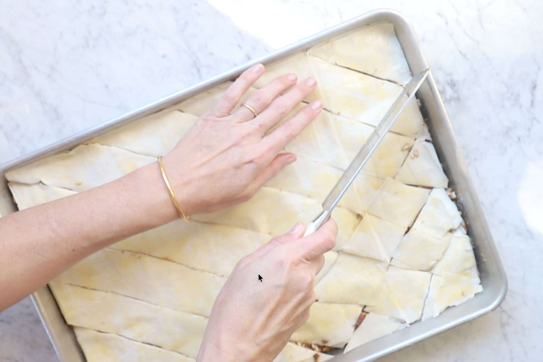 Cutting homemade baklava with a knife before baking it.
