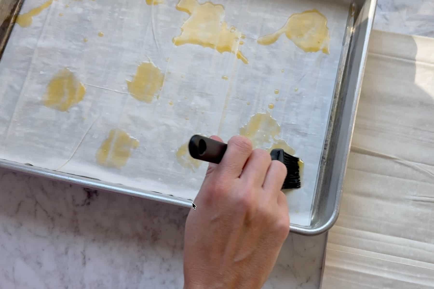 spreading melted ghee on the phyllo sheets.