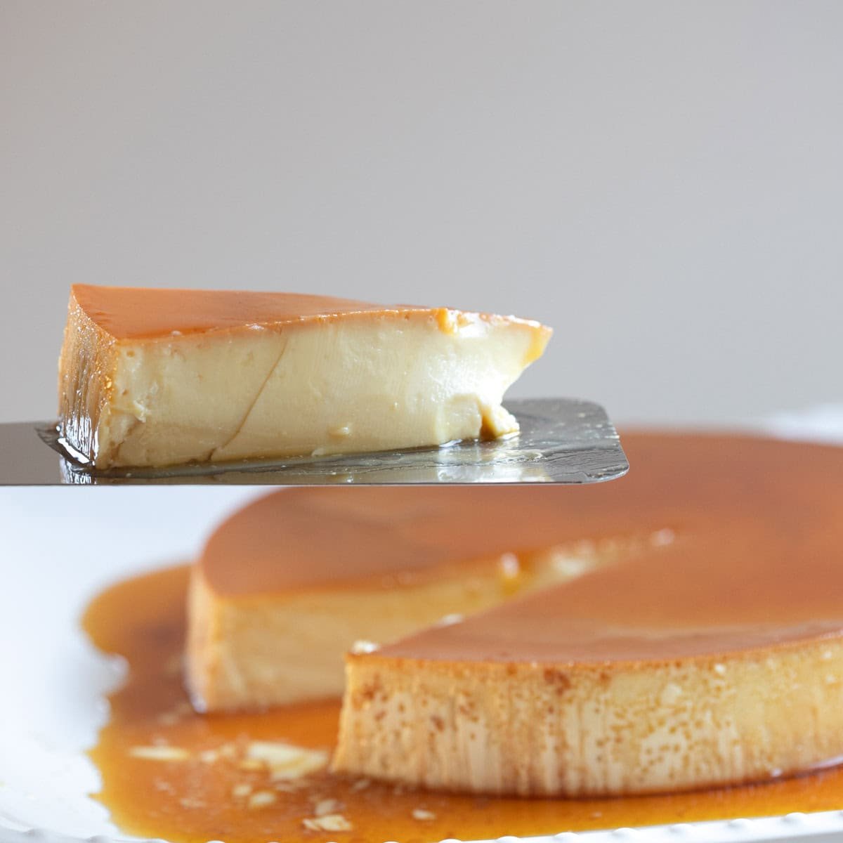 A slice of creme caramel on a spatula.