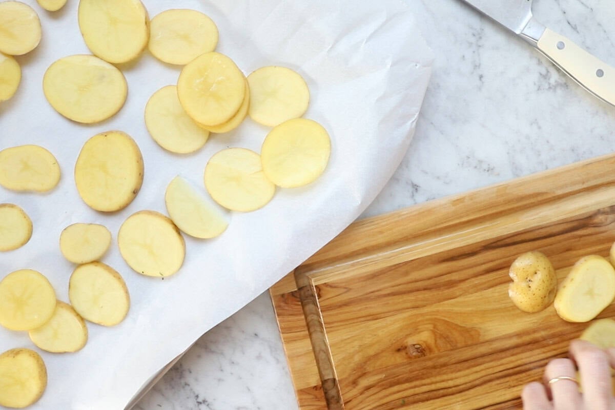 cutting potatoes and placing them on a parchment lined baking sheet.