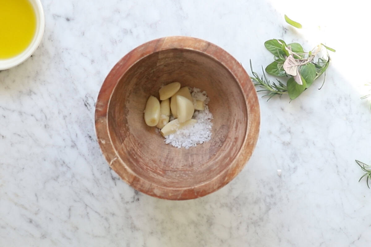 Whole garlic cloves and salt added to a bowl.