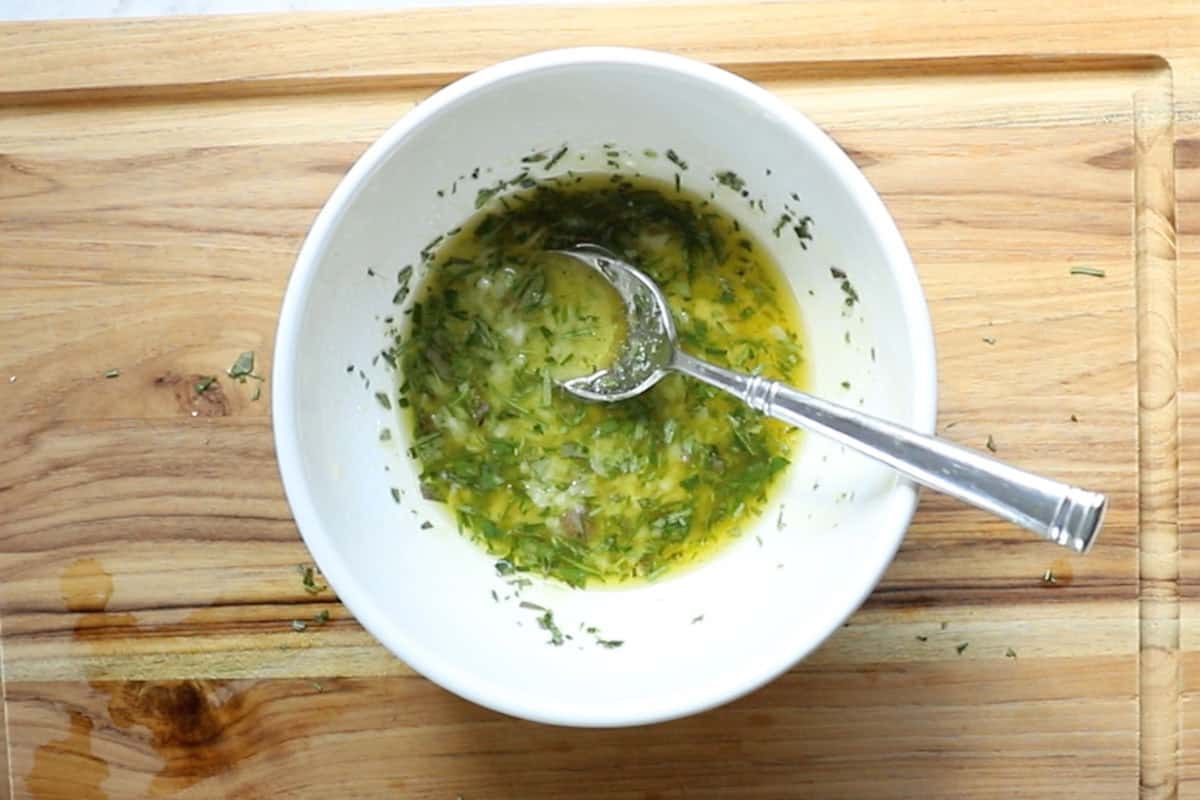lemon juice, crushed garlic, salt, olive oil, and fresh herbs in a bowl.