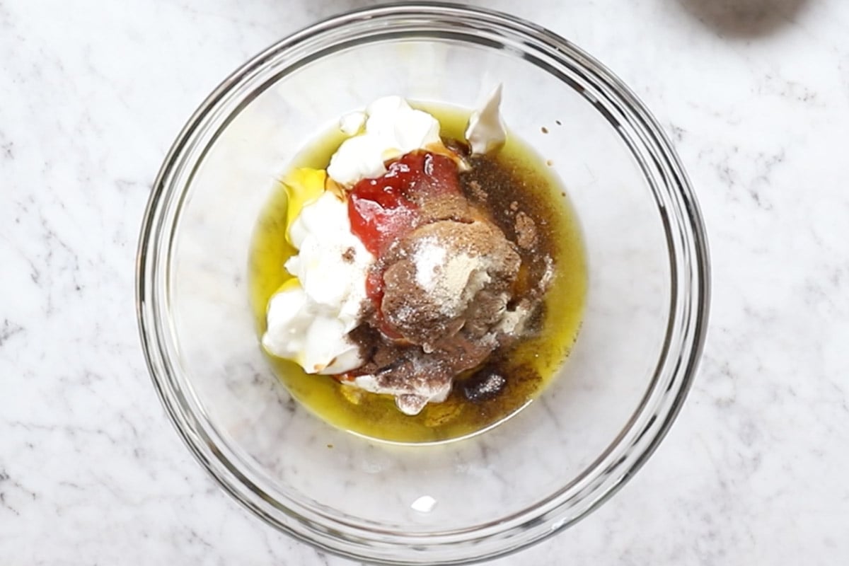 yogurt, olive oil, lemon juice, ketchup, allspice, Lebanese 7 spice, crushed garlic, white pepper, and salt in a bowl.