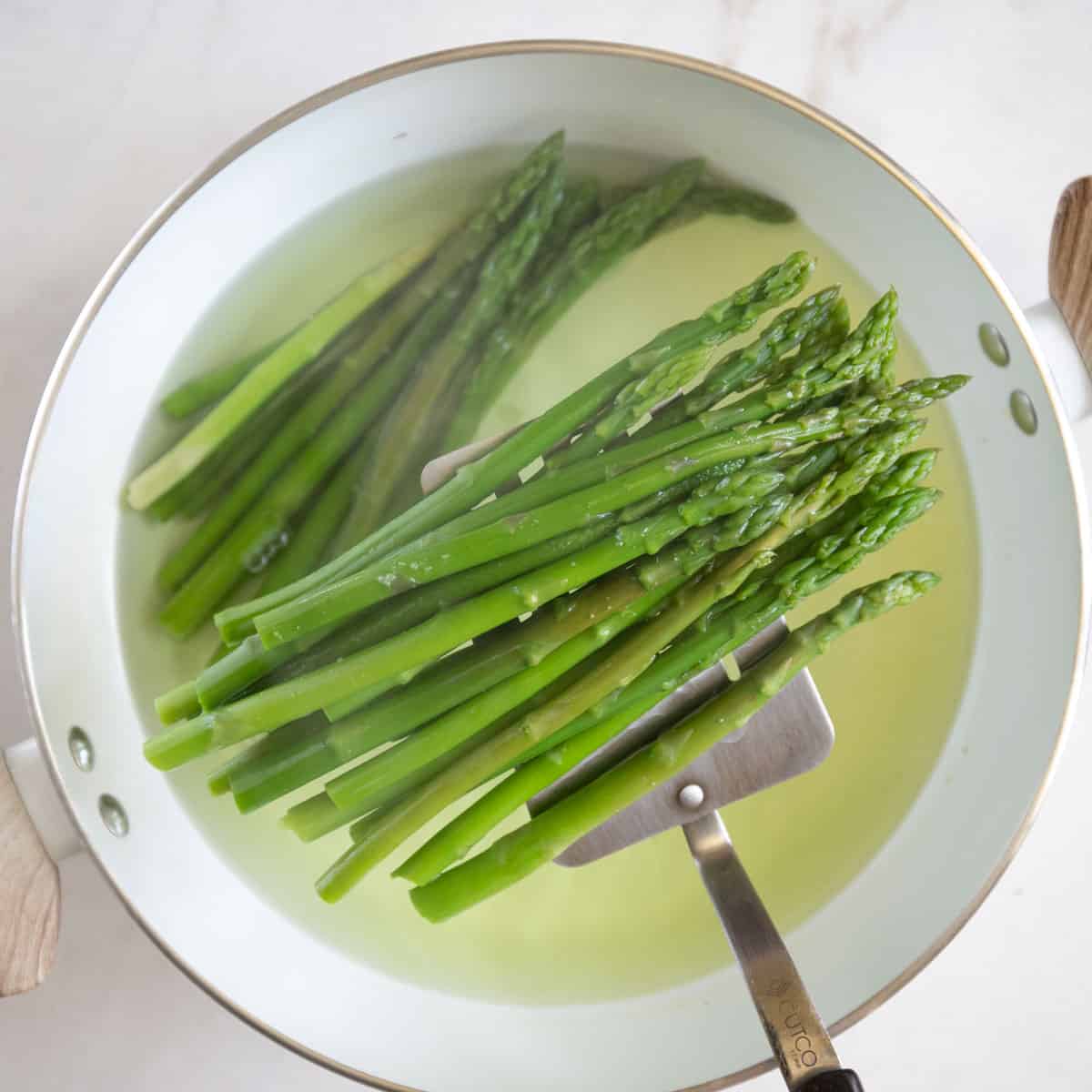 Removing blanched asparagus from boiled water.