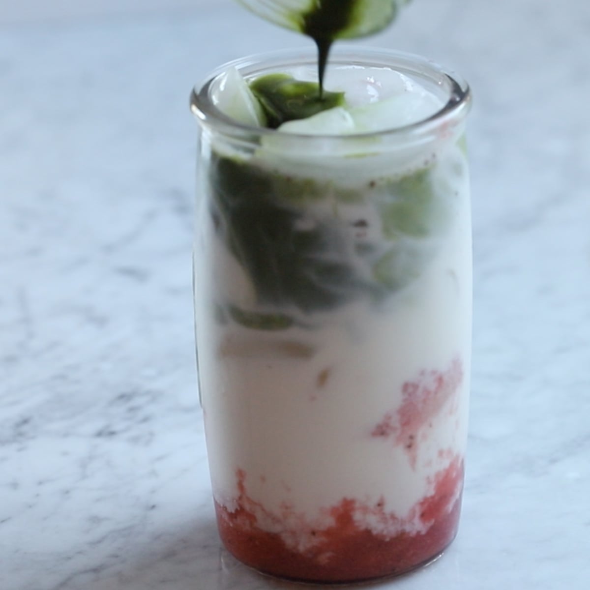 pouring matcha shot onto the strawberry milk