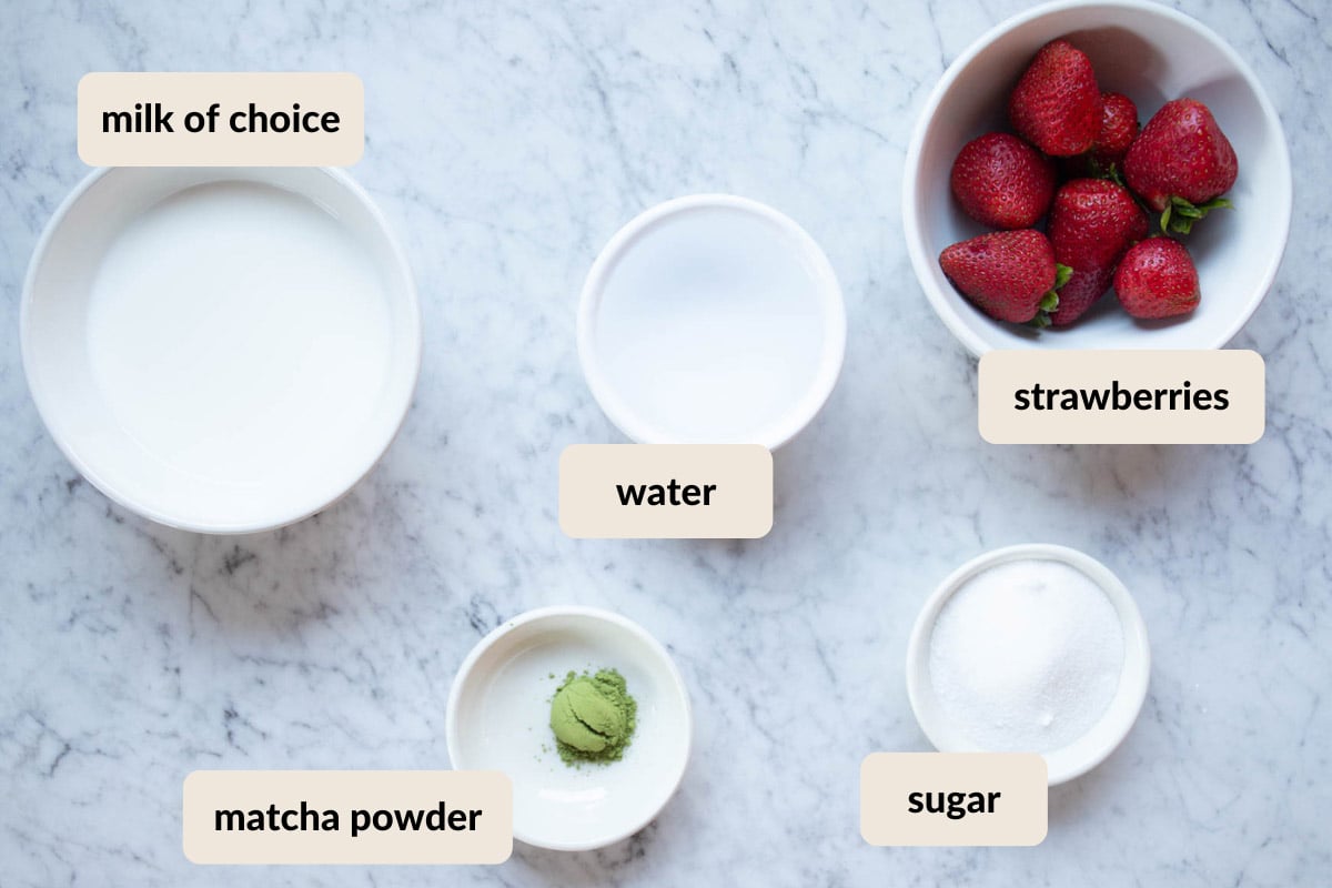 ingredients needed to make an iced strawberry matcha latte which includes, ceremonial grade matcha, milk of choice, fresh strawberries, water, and granulated sugar.